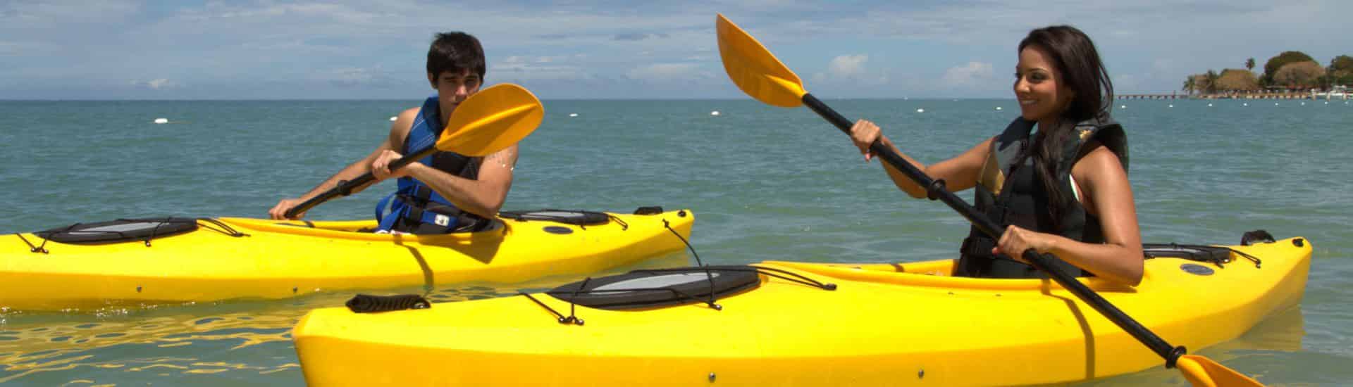 Dos personas en dos kayaks amarillos flotando en agua verde azulada