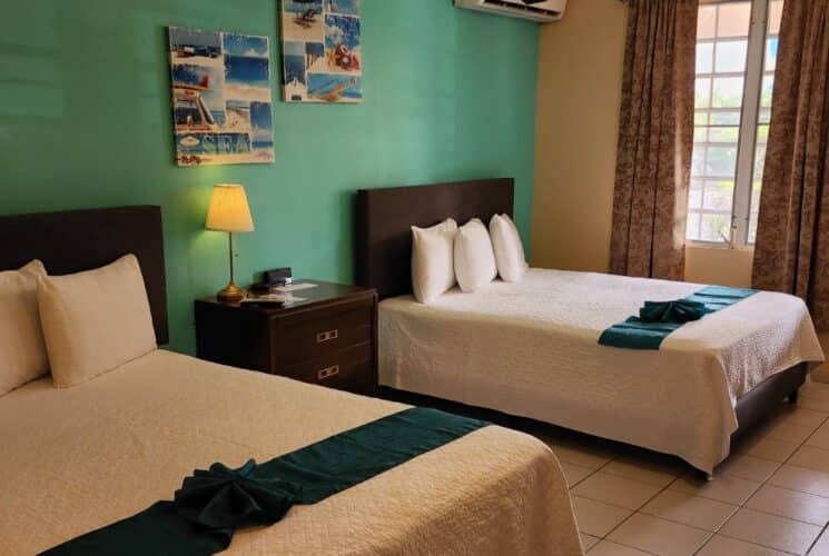 Studio with tan walls, tile flooring, two queen beds with white bedding, and dark wooden furniture