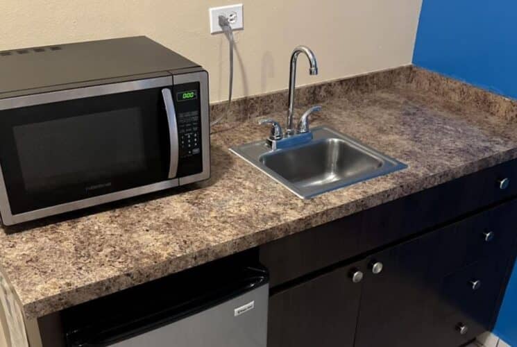 Bedroom with small counter with sink, microwave, and mini fridge