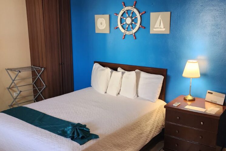 Bedroom with blue and tan walls, tile flooring, dark wooden furniture, and white bedding
