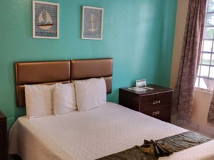Bedroom with turquoise and tan walls, tile flooring, dark wooden furniture, and white bedding