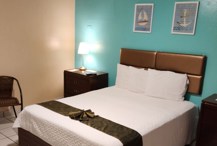 Bedroom with turquoise and tan walls, tile flooring, dark wooden furniture, white bedding, and sitting area